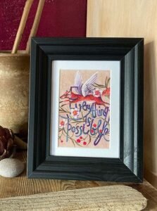 Atvirukas rėme interjere su skrendančia lape ir užrašu "Everything is possible"