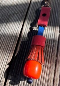 Oranžinis ir mėlynas Raktų pakabukas iš odos ir oranžinio plastiko karolio ant meninių lentučių