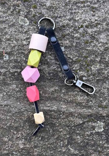 Raktų karoliai iš spalvotų įvairių formų medinių karoliukų, sukomponuoti ant akmens